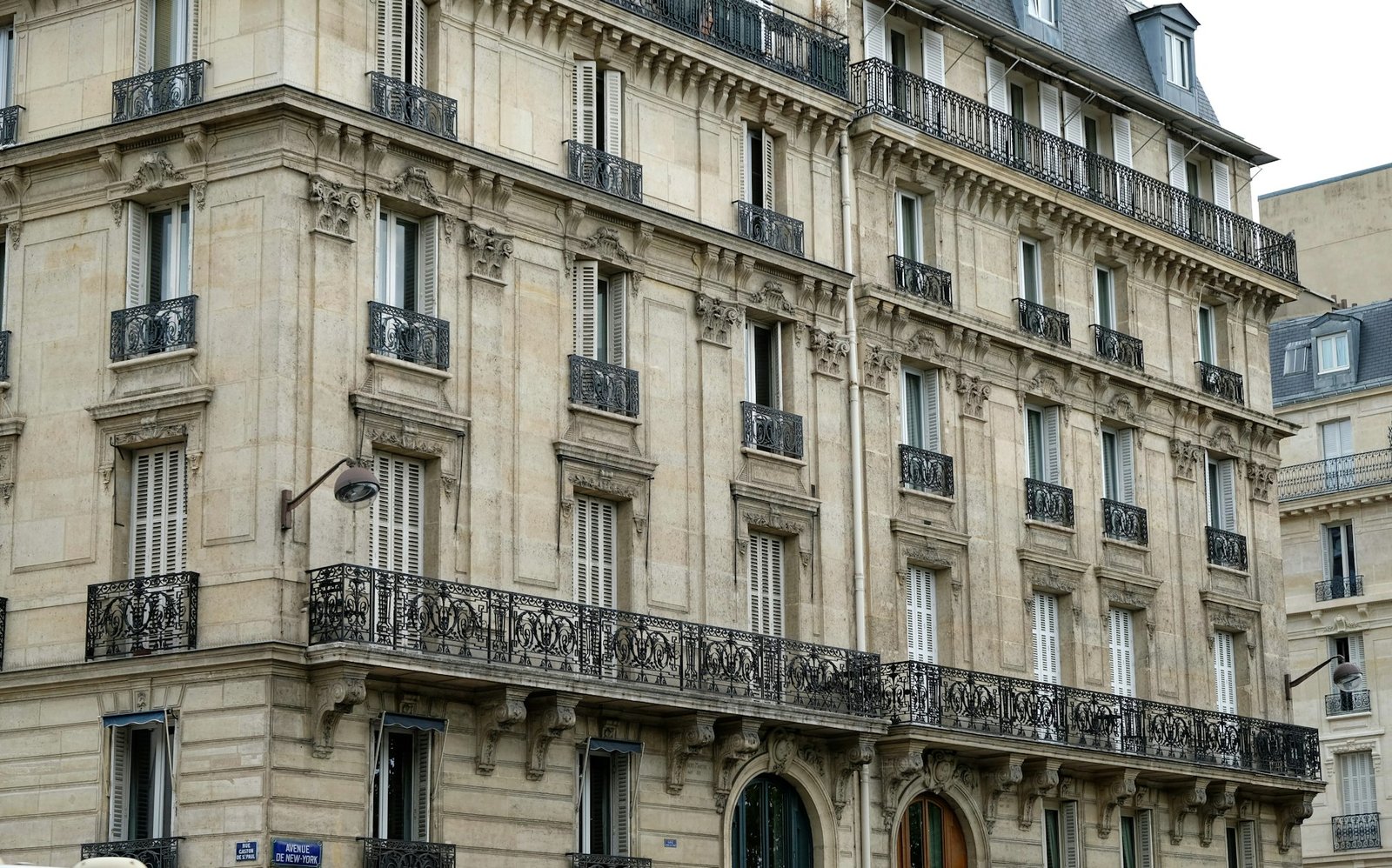 Façade d'immeuble haussmannien avec fenêtres hautes, balcons en fer forgé et volets